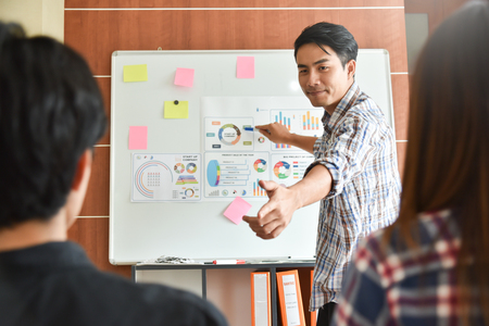 Confident Asian Creative male Designer making a new business presentation project to a group.