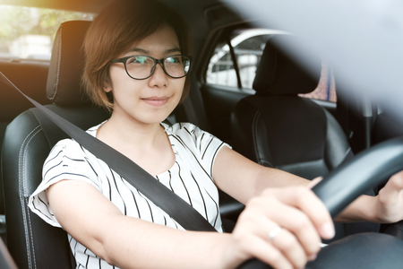 Relaxed Asian woman in glasses driving a car. Success and Happiness Concept. Smiling face.の写真素材