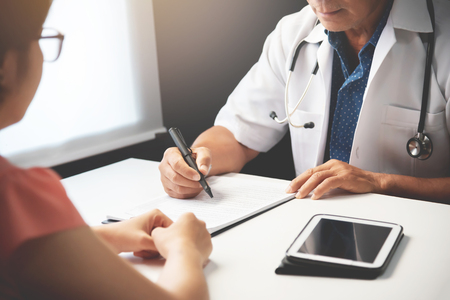 Asian Senior male Doctor discussing with Female patient in medical room.の写真素材