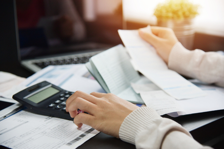 Close up of woman hand calculating her monthly expenses with calculator.  Debt.の写真素材