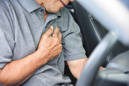 Asian Senior man having chest pain from heart attack while driving a car.  Illness, exhausted,...