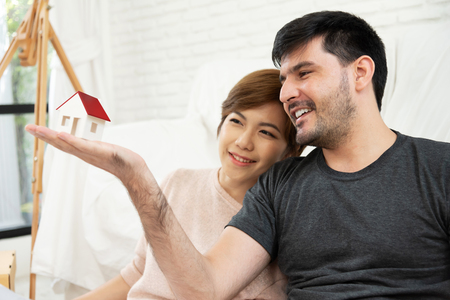 Happy young couple looking to house model together. Smiling.の写真素材
