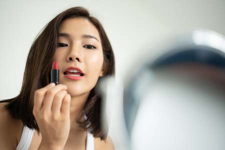Beautiful Asian woman applying red lipstick.の写真素材