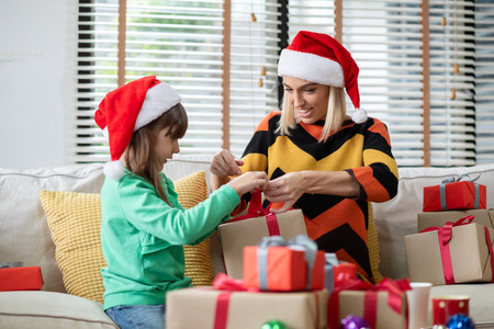 Young mother and her daughter are wrapping gift box for Christmas and New year together.の写真素材