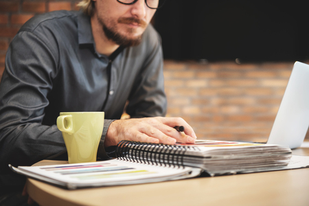 Male Designer wear glasses sitting and looking to color swatch sample at office.の写真素材