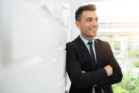Portrait of confident Businessman standing over white wall with copy space. Successful concept. Arm crossed. Looking out to the window.の写真素材