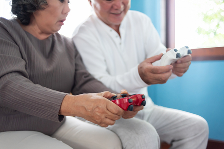 Focus on Hands. Asian Senior Couple holding joysticks and playing video games together.の写真素材