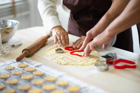 Close up Senior Hands are making cookies with red cutters in heart shape.の写真素材