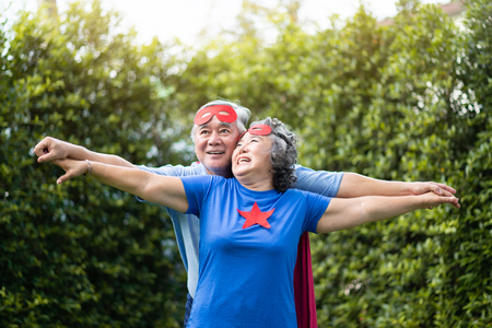 Asian Senior couple in Superhero costume relaxing and celebrating at the park outdoor togetherness.の写真素材