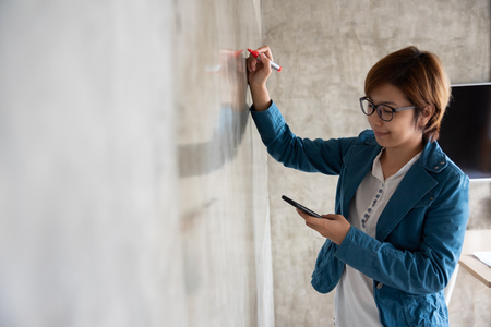 Creative woman in blue shirt drawing on the wall.の写真素材