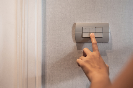 Close up of finger is turning on or off on grey light switch. Copy space.