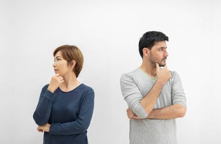 Portrait of young couple standing separately with arms crossed and thinking something on white isolated background. divorce, separated concept.の写真素材
