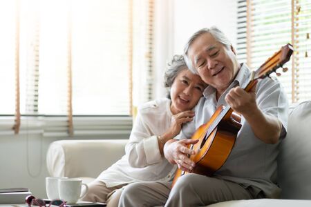Happy Asian senior Couple enjoying with singing and playing guitar together. Having fun.の写真素材