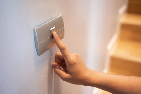 Closeup of finger is turning on or off on light switch at the house. Copy space.の写真素材