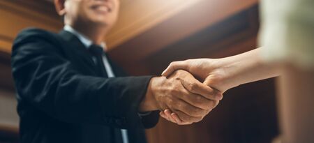 Successful Businessman shaking hands with Businesswoman over wooden wall background at the office. Enjoying Good deals with Negotiation business.の写真素材