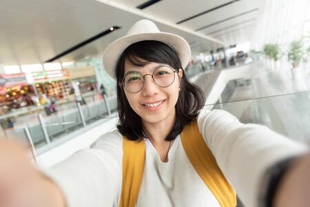 Portrait of young woman traveler wear glasses and hat taking selfie. Happy smiling Girl passenger. Journey, Holiday maker.の写真素材