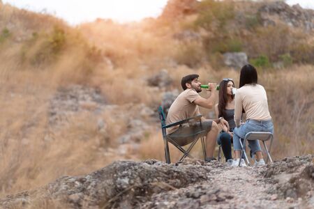 Happy Diversity friends enjoying camping in countryside with sunlight. Group of Multiethnic Traveler sitting relaxing in nature and mountain with copy space.の写真素材