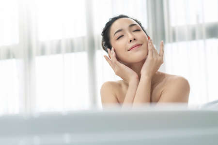 Beautiful Asian woman resting in the tub in the bathroom. Happy Smiling Young Asian female relaxing...