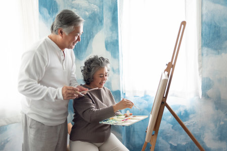 Asian Elderly Couple painting on canvas at their home. Happy Smiling Old man and woman colouring together.の写真素材