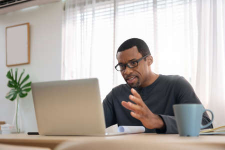 African American man having video conference with colleague at home. Black African Male freelancer...