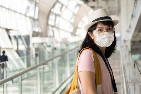 Portrait of Asian female traveler wearing protective face mask while traveling in international airport terminal during pandemic.の写真素材