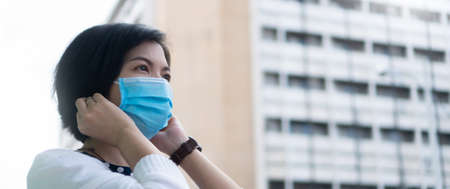 Asian Female wearing protective face mask at outdoor in the city while pandemic. Banner and Copy Space.の写真素材