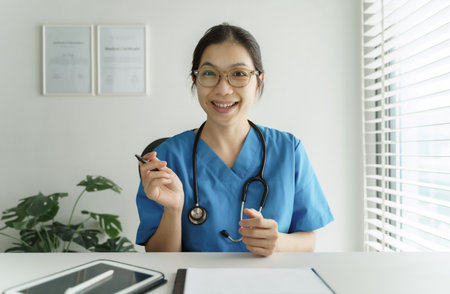 Asian Female Doctor making online video chat giving advice and consultation with her patient at the hospital.の写真素材
