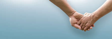 Senior couple holding hands together on isolated blue background. Lover, valentine's day concept. Banner.の写真素材