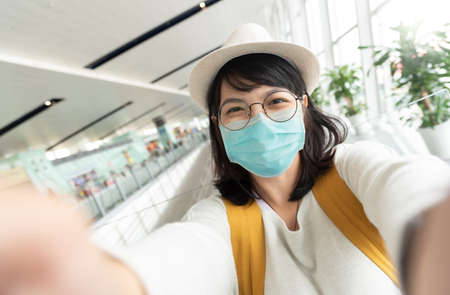 Portrait of Asian Young Female tourist wearing protective face mask taking selfie.の写真素材