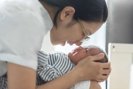 Asian Young mother playing with her little baby at home.の写真素材