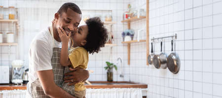 Portrait of Happy African American father and his son while cooking at kitchen, Loving Black little Boy embracing and kiss his Dad, Banner, Panoramicの写真素材