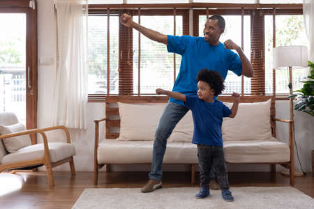 Happy African American Father and Afro boy playing at home together, Black family having fun, Power of Superhero, Single Dad, Father's day conceptの写真素材