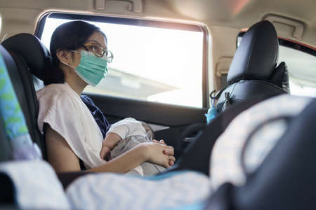 City Life, Asian Mother wearing Protective face mask holding newborn baby boy while sitting in the car, Young Mom breastfeeding her son during coronavirus pandemicの写真素材