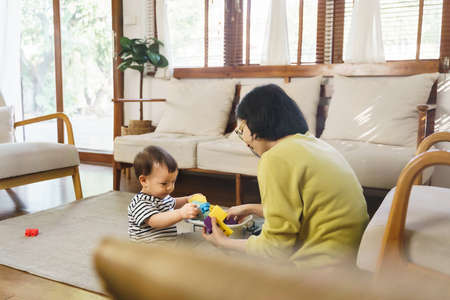 Happy Asian little boy playing blocks toy with his Mother at home.の写真素材