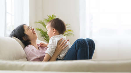 Portrait of Asian young mother with small son laughing playing together.の写真素材
