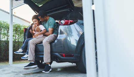 African American Father and son sitting in car trunk, Happy family on road trip.の写真素材