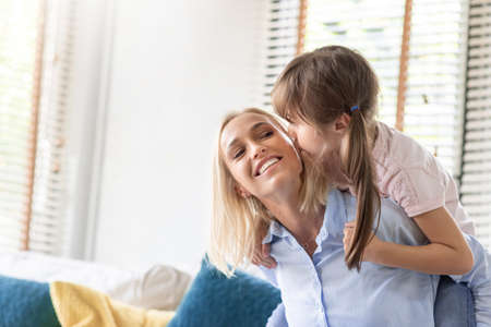 Little Daughter kissing and hugging happy mother on Mother's day at home.の写真素材