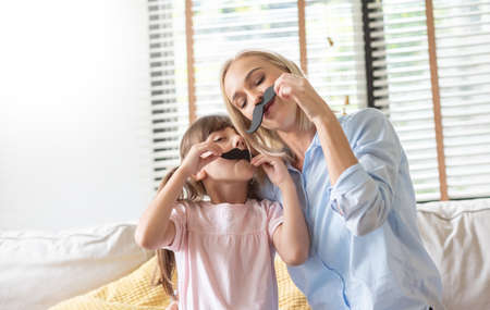 Funny Mother and daughter playing paper moustaches together.の写真素材