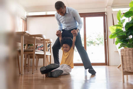 African American Father and his little son playing on the floor at home together.の写真素材