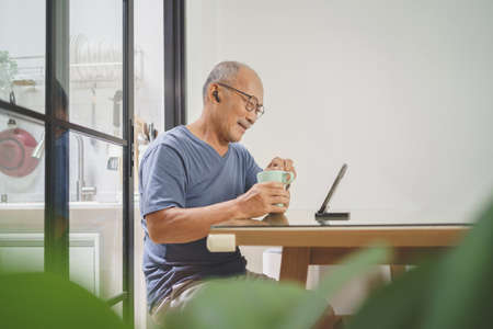 Happy smiling Senior adult man wearing eyeglasses sitting using smartphone at home, Leisure, Active...