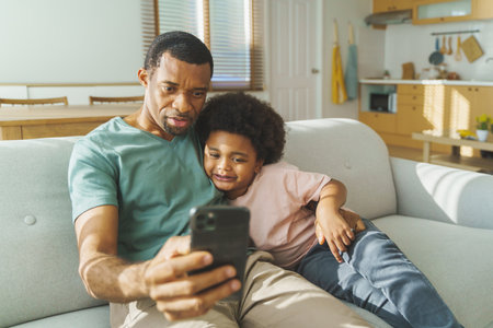 Black African American father and son using smartphone at home. Happy smiling African Man and little child having video callの写真素材