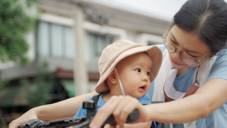 Portrait of Young Asian woman and her toddler son riding the bicycle outdoor, Happy Chinese mother and her boy cycling togetherの写真素材