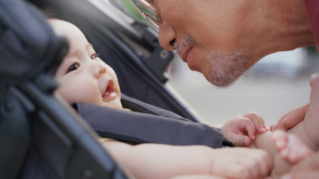 Asian little Adorable Baby boy in baby stroller playing with his Grandfather while walking in the park at outdoor together. Loving Different Family generations.の写真素材