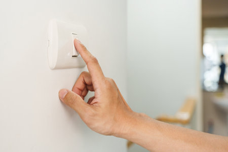 Closeup of finger is turning off on lighting switch on white wall at home. Power, Energy, Saving Electrical, Copy space.の写真素材