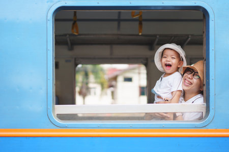 Happy Asian little boy and mother Laughing while traveling by train, Playful Child with big smile.の写真素材
