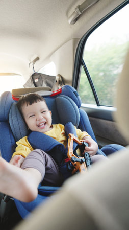 Cheerful Happy smiling Asian little boy in safety car seat, Happy small child travel by car with family.の写真素材