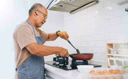 Happy retired Asian Mature Adult male cooking vegetables in frying pan at kitchen, Healthy Food, Prepare Foodの写真素材