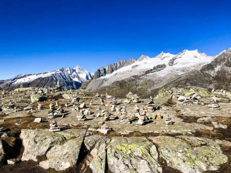 A lot of Stone towers with snowcapped Mountains with blue sky at Bettmeralp, Switzerlandの写真素材