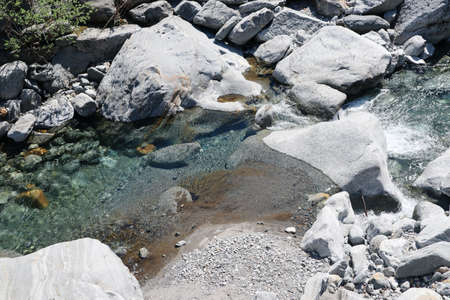 Stones and Rocks in the blue water of the Bavona River flowing through the Valley in the Ticino in Switzerlandの写真素材