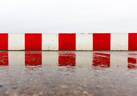 Red white concrete wall on the wet asphaltの写真素材